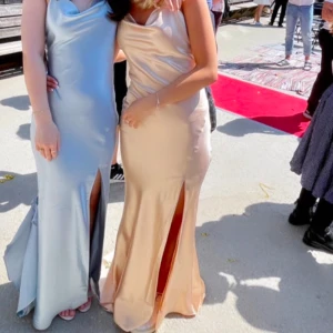 Champagnefärgad långklänning - Jätte fin champagnefärgad långklänning i satin med slits! Perfekt för balen!! Klänningen har några få fläckar, kom privat för bilder! Tryck inte köp nu, Buda!!