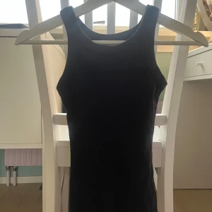 Svart ärmlös linnetopp - Säljer en stilren svart ärmlös linnetopp. Perfekt för lager-på-lager eller att bära som den är. Enkel och mångsidig design som passar till det mesta.