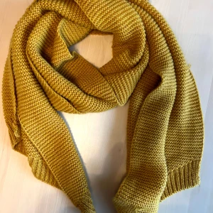 Gul stickad halsduk från Pieces - Säljer en snygg gul stickad halsduk från Pieces. Den är perfekt för att hålla dig varm under kyliga dagar. Halsduken har en enkel och stilren design med ribbade kanter. Liten defekt på ett ställe (bild 4)
