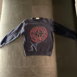 Mörkblå sweatshirt från Stone Island Junior - Säljer en snygg mörkblå sweatshirt från Stone Island Junior med ett logotryck på framsidan. Tröjan har långa ärmar och rund halsringning. Perfekt för en stilren look. Köpt på NK.