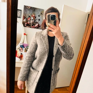 Grå ullkappa från Monki - Säljer en snygg och varm grå ullkappa från Monki. Den är långärmad och har en normal passform. Kappan har knappar framtill och två fickor. Perfekt för höst och vinter! 🧥