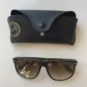 Ray-Ban solglasögon med fodral - Säljer ett par snygga Ray-Ban Boyfriend solglasögon i brun färg med ett matchande svart fodral. Glasögonen är tillverkade i Italien och har en klassisk design med bruna linser. Perfekta för soliga dagar! RB 4147
