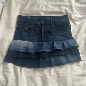 Jeanskjol med volanger - Säljer en superfin jeanskjol med volanger! Den är mörkblå och har en cool lager-på-lager design med olika nyanser av blått. Säljer pågrund av att den är för liten för mig. Använt några få gången.