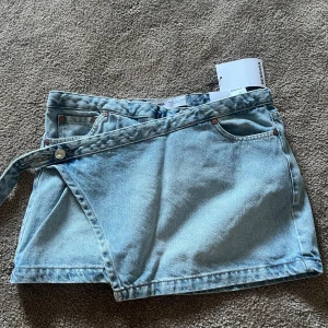 Bershka jeans kjol  - Superfin jeans kjol, köpt på bershka. Perfekt blå färg och en snygg annorlunda knäppning ! 🩵 Är i storlek 32 men skulle säga passar en 34 också ! 