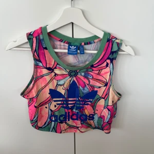 Träningstopp från adidas - Jättefin och färgglad tränings topp, så luftig och skön. Relativt kort i modellen men väldigt skön.