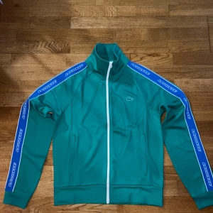Lacoste Zip Up Tröja. - Lacoste tröja säljes pga inte min stil, stl S man, använd 1 gång. Pris går diskuteras vill bli av med den.