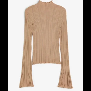 Beige ribbad tröja - Säljer en superfin beige ribbad tröja med långa ärmar. Den har en hög krage och är i ett mjukt material som känns skönt mot huden. Perfekt för höst och vinter! Tröjan har en snygg passform och är både stilren och bekväm.