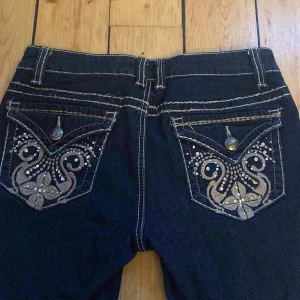 Lowwaist bootcut jeans med broderier på fickorna - Jättesnygga lowwaist bootcut jeans med super snygga detaljer på fickorna och sömmarna!! Innerbenslängd är 79cm, midjemåttet är 37 cm tvärs över och det är 20 cm från skrevet upp!