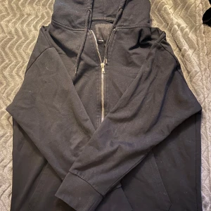 Svart hoodie med dragkedja från 157 - Säljer en svart zip-up hoodie från Lager 157 i storlek S. Den har en dragkedja framtill och en skön huva. Perfekt för en avslappnad stil och passar bra till både vardag och chill. 💗