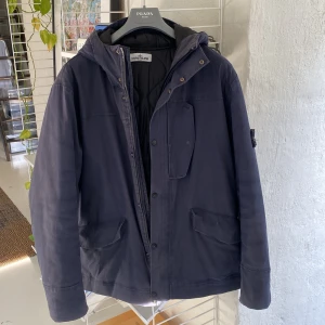 Stone Island vinterjacka - Navy vinterjacka från Stone Island. Vatten och vindsäker med Primaloft insiulation. Inköpt för ca 9 år sedan, ej använd på 6. Blixtlåset sönder, funkar utmärkt med enbart knappar. Lite slitage längst ner på ärmslutet, märks ej. 2XL men mer som XL. 