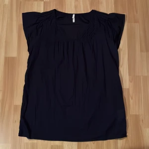 Marinblå blus från Sisters - Säljer en stilren marinblå blus från Sisters i storlek 42. Den är tillverkad i 100% bomull vilket gör den superbekväm och perfekt för både vardag och fest. Blusen har en lös passform och korta ärmar, vilket gör den luftig och skön att bära. Perfekt för alla säsonger!