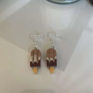 Glassformade örhängen - Supergulliga örhängen formade som små glassar i brunt och beige. Perfekta för att ge en lekfull touch till din outfit. De är lätta och bekväma att bära hela dagen. Passar perfekt för sommarens alla äventyr eller bara för att liva upp vardagen!