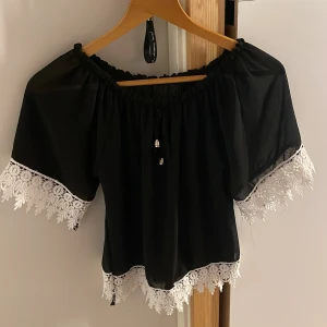 Svart genomskinlig blus - Super söt blus, dock lite genomskinlig. Vita detaljer på ändarna samt två stycken guld detaljer som hänger ner där i mitten. Köpt utomlands så finns ej märke! 🖤 allt är i bra skicka inga hål osv 
