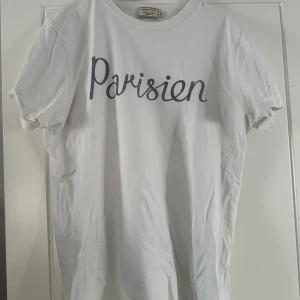 Vit t-shirt från Maison Kitsuné - Vit t-shirt från Maison Kitsuné med texten 'Parisien' i blått på framsidan. Pris kan diskuteras vid snabb affär. Hör av dig vid fler frågor👍