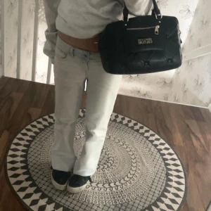 Ljusblå jeans med slitningar - Säljer ett par ljusblå jeans med slitningar på låret. De har en bootcut-stil och är lågmidjade. Perfekta för en avslappnad look.