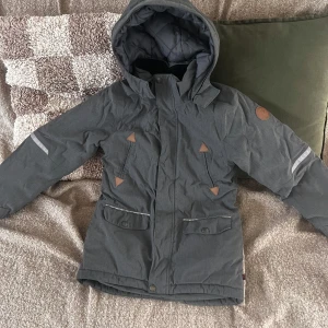 Polarn O. Pyret vinterjacka - Vinterjacka från Polarn och pyret. Stl 128.  Grå.  Hängöglan behöver sys fast annars är jackan i fint skick.  400 kr