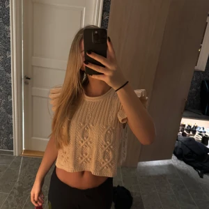 Beige stickad topp från Zara - Säljer en söt beige stickad topp från Zara med korta ärmar och ett fint mönster. Toppen är croppad och har volangdetaljer på ärmarna. Perfekt för en stilren look!