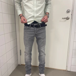 Jack & Jones slim jeans - Säljer ett par grå jeansbyxor med en klassisk femficksdesign. Byxorna har en slim fit passform och är tillverkade i ett slitstarkt material. Perfekta för en avslappnad stil.