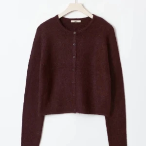 Vinröd kofta  - Snygg vinröd kofta med rund hals och knäppning framtill. Perfekt för kyliga dagar och enkel att matcha med olika outfits. Långärmad och mjuk i materialet.