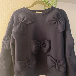 Blå tröja med rosetter från Nina Kendosa - Säljer en blå tröja från Nina Kendosa Paris med flera stora rosetter som dekoration.💙