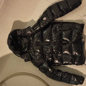 Svart pufferjacka från Moncler - Snygg svart pufferjacka från Moncler med glansig design. Säljer den billigt har haft den länge men den har mest legat i garderoben 