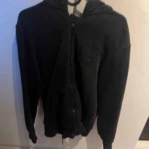 Svart hoodie med dragkedja - Säljer en svart hoodie med dragkedja och huva. Perfekt för kyliga dagar och enkel att matcha med olika outfits.
