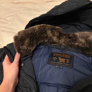 Jacka från Woolrich - Hej, säljer en Woolrich jacka i Marinblått med päls  i storlek Large (L). Fin jacka som passar bra nu till vintern när det blir kallt. Kommer tyvärr inte till användning hos oss utan säljer den till någon som behöver den bättre.  Den är använd men i fint skick. Finns två små fläckar på baksidan men inget som stör.  Skickas med spårbar frakt. 