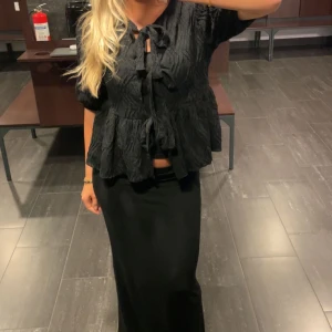 Svart topp med knyt  - Elegant svart topp ifrån ginatricot med knyt framtill och volangdetaljer. Använd Max 3 gånger💕