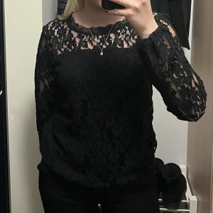 Svart spetsblus - Elegant svart spetsblus med långa ärmar och vacker spetsdetaljering. Perfekt för en stilren look.