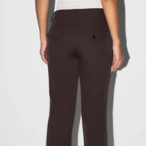 Bruna kostymbyxor - Snygga bruna kostymbyxor med hög midja och raka ben. Byxorna har knappar fram och fickor bak, vilket ger en stilren look. Perfekta för en elegant och professionell stil.