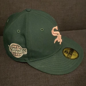 Baseball keps, Grön från New Era - Snygg grön keps från New Era med broderad logotyp och World Series-märke. Perfekt för sportfantaster och samlare. Kepsen har en klassisk design med böjd skärm och ventilationshål.