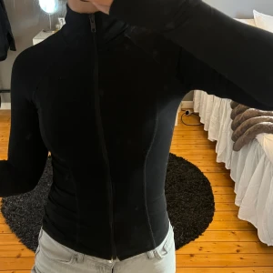 Träningströja - Snygg svart tight tröja med dragkedja framtill. 