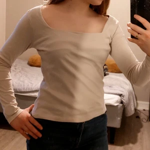 Sinsay Beige shirt - Säljer en stilren beige långärmad topp med en fyrkantig halsringning. Perfekt för en minimalistisk look och passar bra till både jeans och kjol.