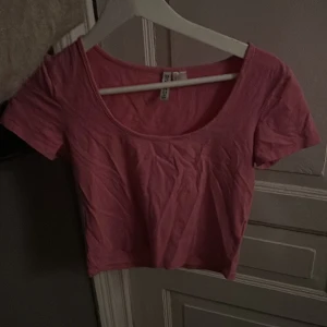 Rosa croppad topp från H&M - Säljer en söt rosa croppad topp från H&M:s Divided-kollektion. Toppen har korta ärmar och en rund halsringning, perfekt för sommardagar.