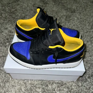 Nike Air Jordans i svart, blå och gul - Snygga Nike Air Jordans i en cool färgkombination av svart, blå och gul. Skorna har en klassisk design med snörning och den ikoniska Jumpman-loggan på plösen. Perfekta för dig som vill sticka ut med stil.