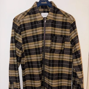 Rutig overshirt från LEGENDS - Säljer en snygg rutig jacka från LEGENDS i gul och svart. Den har en dragkedja framtill och en bröstficka. Perfekt för höst och vår. Köpt för 1200kr. L herrstorlek.