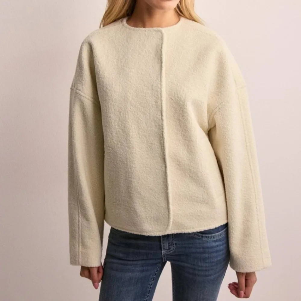 Säljer en superfin beige ulljacka med en stilren design. Jackan har en rund hals och knappar framtill. Perfekt för höst och vår, och den har en normal passform. Den är långärmad och ger en elegant look till vilken outfit som helst. . Jackor.