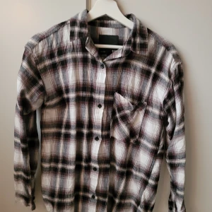 Rutig skjorta från lager 157 - Säljer en snygg rutig skjorta från lager 157 i storlek XS. Skjortan har en klassisk svart, vit och grå färgkombination med långa ärmar och knappar framtill. Perfekt för en avslappnad stil eller lager på lager under hösten. Den är i mycket bra skick och redo för nya äventyr! Skjortan är också oversized så de passar storlek S och M också beroende på passform.🍁