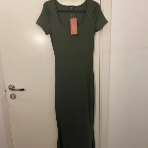Klänning  - Militärgrön långklänning i super skönt tyg som sitter tight men känns inte alls att den sitter åt.  Lite sjöjungfru effekt i nedre delen av klänningen då den går ut lite.  Helt oanvänd 