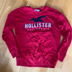 Säljer en snygg röd tröja från Hollister med deras ikoniska logga på bröstet. Perfekt för en avslappnad stil och passar bra till både jeans och shorts. Tröjan har långa ärmar och är i ett mjukt material som känns skönt mot huden. Perfekt för höst och vår!