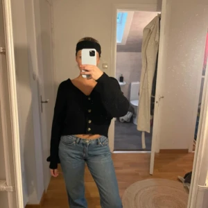 Svart kofta med knappar - Säljer en svart kofta med knappar framtill. Den är croppad och har långa ärmar, perfekt för höst och vår. Koftan är i bra skick och passar till både vardag och fest. Supermysig och lätt att matcha med olika outfits!