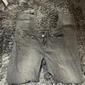 Grå jeans från JSFN - Säljer ett par snygga grå jeans från JSFN i storlek 32. De har en klassisk femficksdesign med knapp och dragkedja framtill. Perfekta för både vardag och fest! 🖤