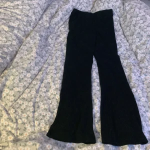 Svarta ribbade byxor från H&M - Säljer ett par svarta ribbade byxor från H&M. De har en skön och stretchig passform med bootcut. Perfekta för både vardag och fest!