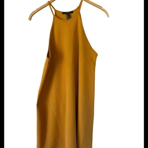 Gul ärmlös klänning från Forever 21 - Snygg gul ärmlös klänning från Forever 21 i storlek S. Perfekt för sommardagar eller en avslappnad fest. Klänningen har en enkel och stilren design med en lös passform som ger en bekväm känsla. Tillverkad i ett lätt och luftigt material.