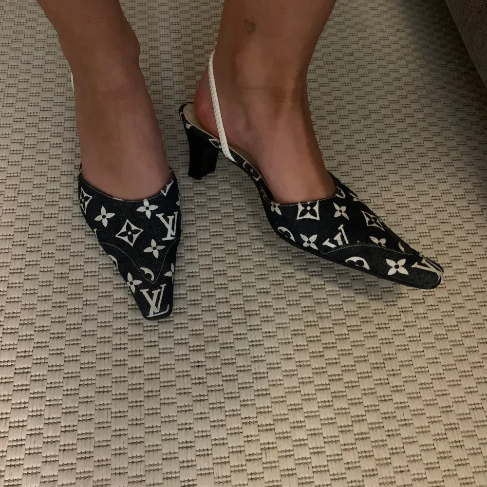 Snygga svarta pumps med vit monogramdesign. De har en spetsig tå och en elegant klack. Perfekta för en stilren look på festen eller middagen. Skorna har en bekväm passform med en smal rem runt hälen.. Skor.