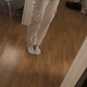 Vita cargopants - Säljer ett par vita cargopants med flera praktiska fickor på sidorna. Byxorna har en loose passform och är perfekta för en avslappnad stil. De är tillverkade i ett bekvämt material som passar bra för vardagsbruk.