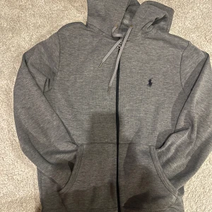 Grå hoodie från Ralph Lauren - Säljer en stilren grå hoodie från Ralph Lauren. Den är grå och logan är svart. Den är i storlek XS och är stilren.