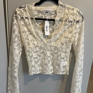 Vit spetsblus från Venderby's - Säljer en elegant vit spetsblus från Venderby's i storlek S. Blusen har långa ärmar och en v-ringad design. Perfekt för att lägga till en romantisk touch till din outfit. Köpte fel storlek så den är endast prövad 🫶✨