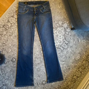 Blå bootcut jeans från Lee - Snygga blå bootcut jeans från Lee med klassisk femficksdesign och låg midja🥰 slitningar vid slutet av benen men inget man tänker på enligt mig💗tveka inte att skriva om du har frågor!