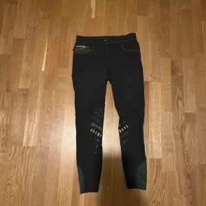 Svarta ridbyxor från Horse Life - Snygga gröna ridbyxor från Horse Life med broderade detaljer och dragkedja på bakfickorna. De är i väldigt bra skick!Byxorna har en tight passform och är perfekta för ridning. De är i storlek 158 så de passar nog någon som är 155-160 cm lång. Säljer pga att de tyvärr blivit för små!❤️De har även förstärkningar vid knäna för extra hållbarhet. Nypris:799 kr. Priset går att diskutera. Hör av er om frågor!❤️